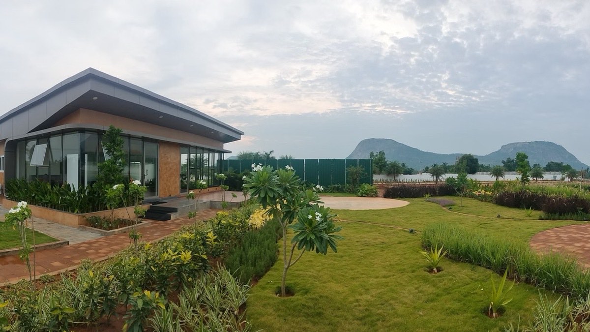 Landscaped gardens and a glass-fronted pavilion at Montira, with Nandi Hills beyond